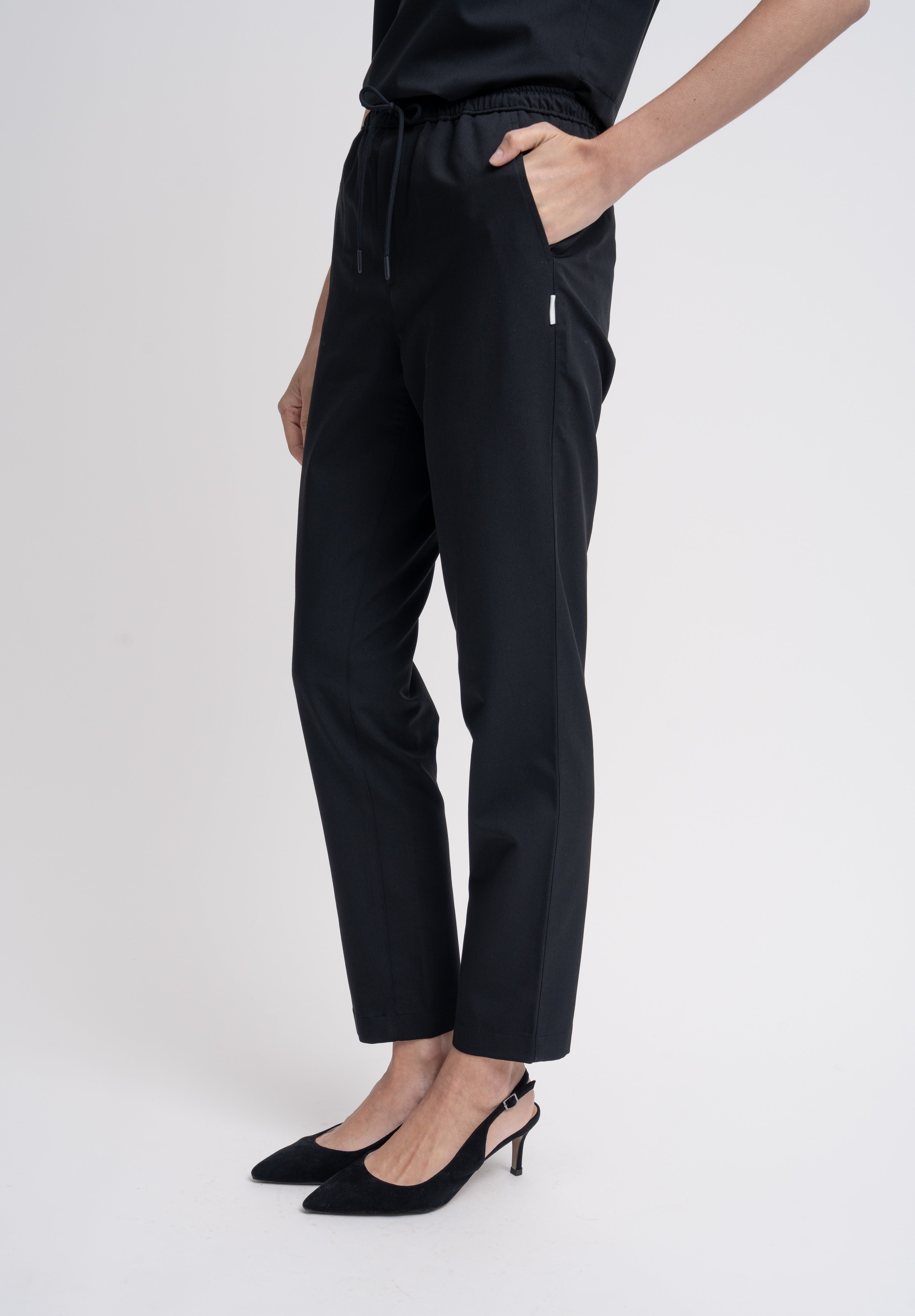 Women's scrub pant in black, front view, half body.