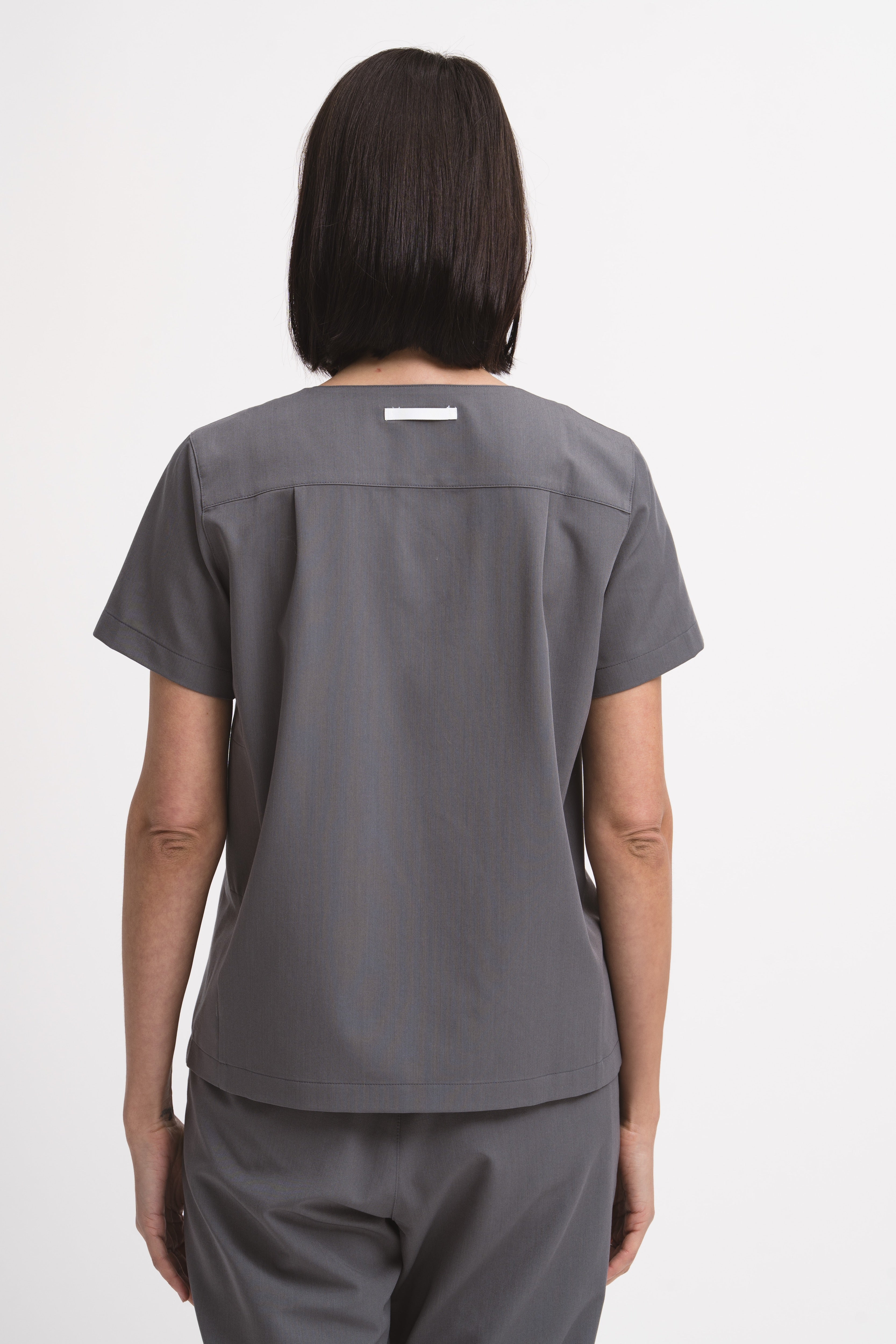 Women's V-neck scrub top in grey, back view, quarter body.