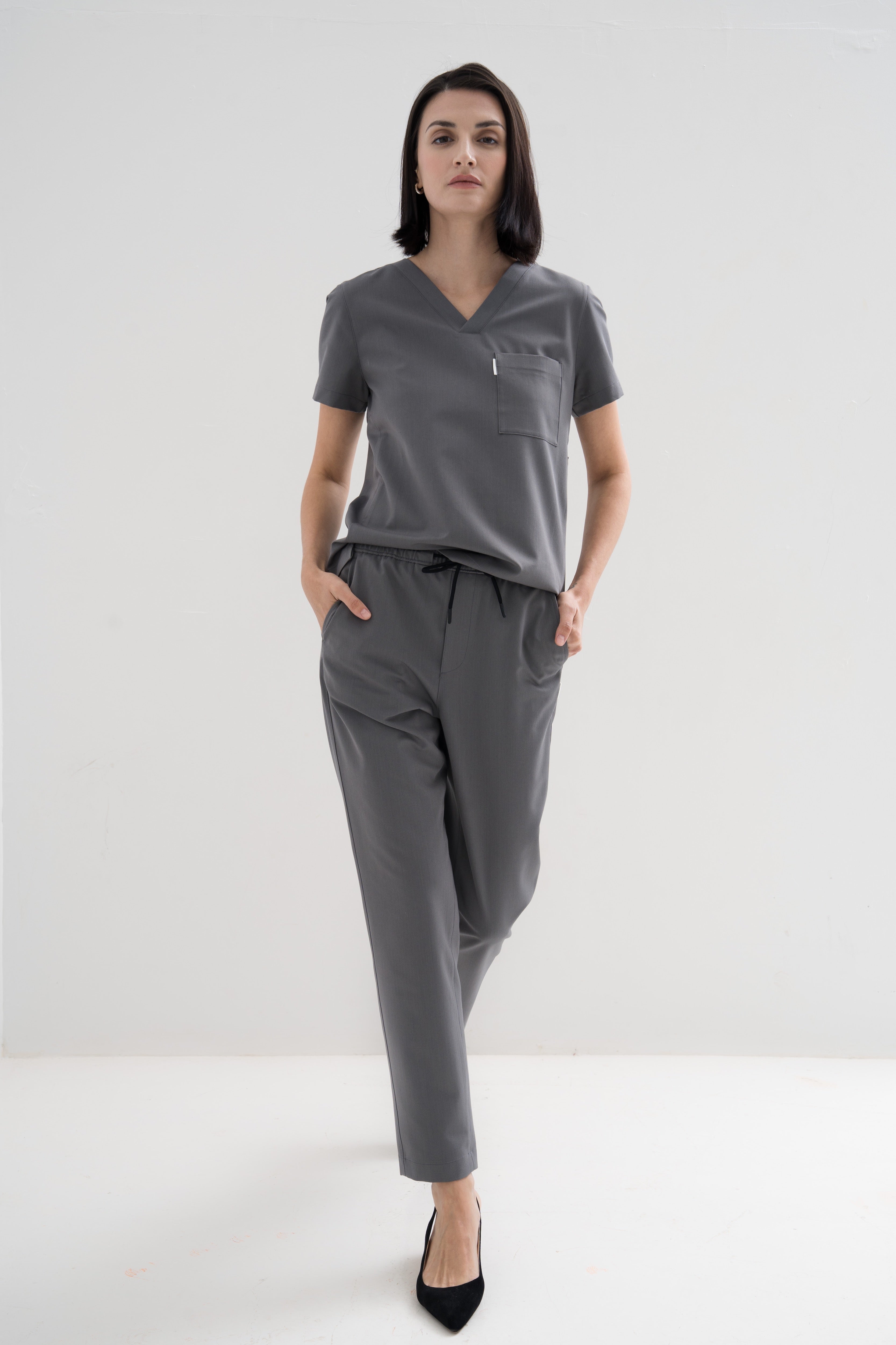 Women's V-neck scrub top in grey, front view, full body.