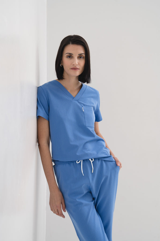 Women's jogger scrub pant in Sailor Blue, styled half body view shown with matching V-neck scrub top for a complete look.