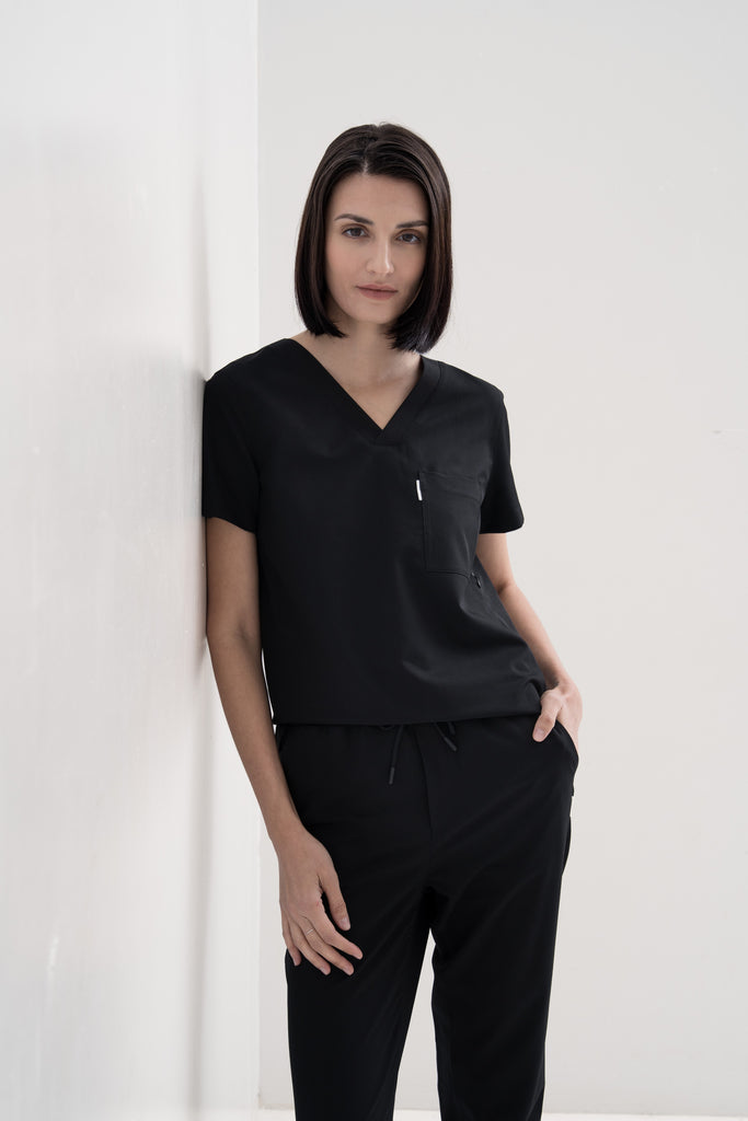 Women's scrub pant in black, styled half body view.