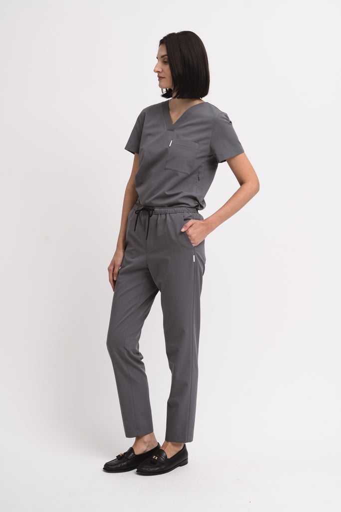 Women's scrub pant in grey, styled half body view.