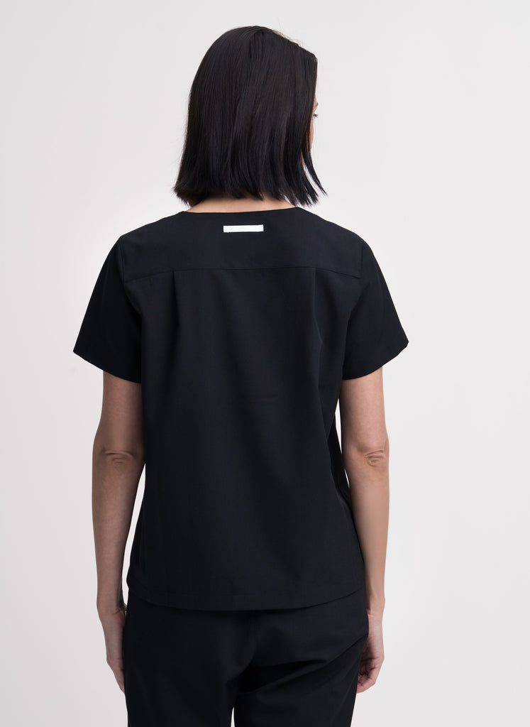 Women's V-neck scrub top in black, back view, quarter body.