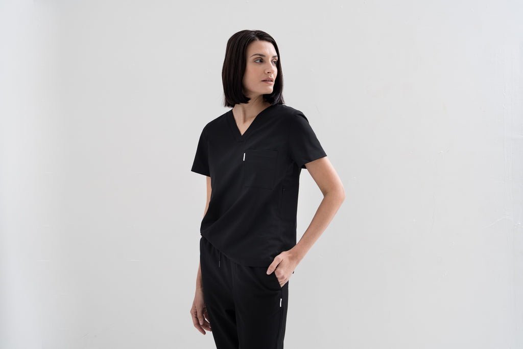 Women's V-neck scrub top in black, front view, half body.
