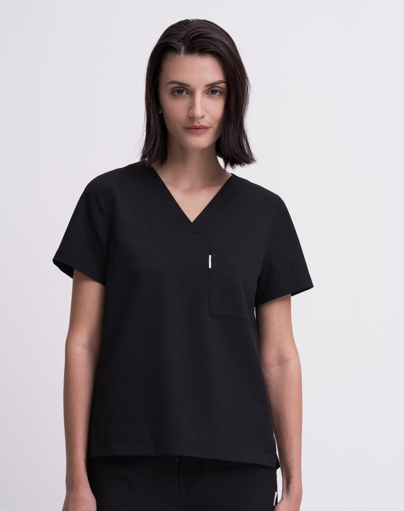 Women's V-neck scrub top in black, front view, quarter body.