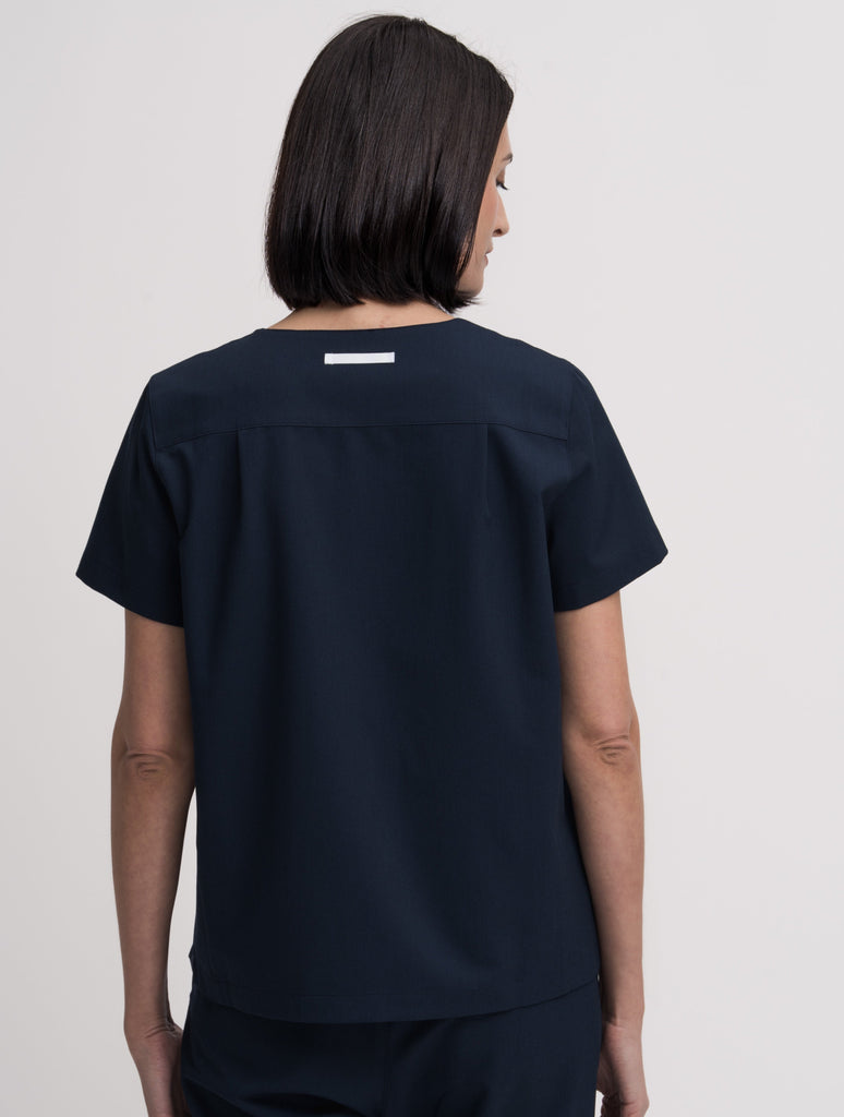 Women's V-neck scrub top in navy, back view, quarter body.