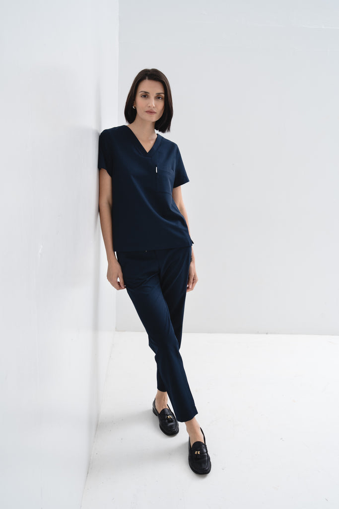 Women's V-neck scrub top in navy, front view, full body.