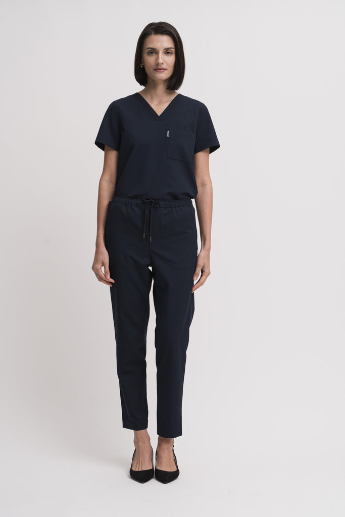 Women's V-neck scrub top in navy, front view, tucked full body.