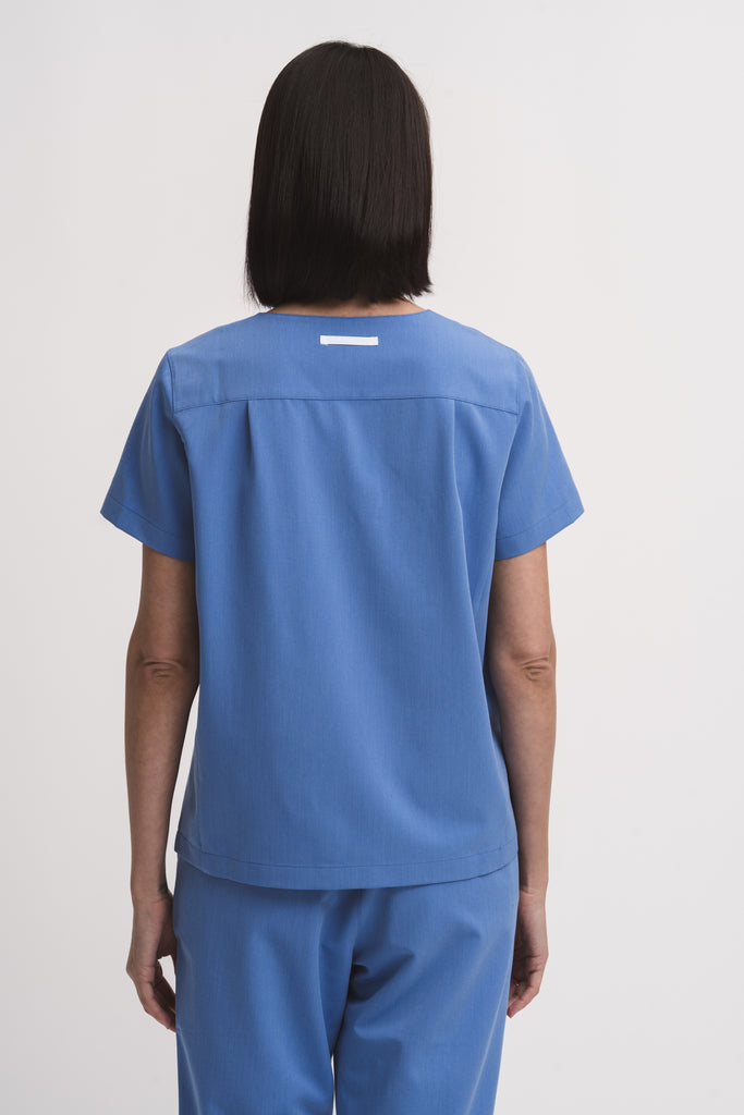 Back view of women's V-neck scrub top in Sailor Blue, full body.